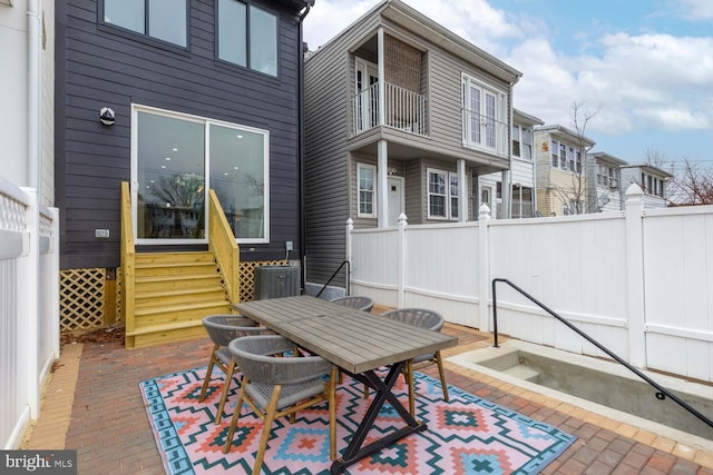 view of patio with entry steps, outdoor dining area, fence, and a balcony