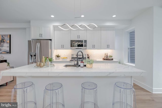 kitchen featuring tasteful backsplash, appliances with stainless steel finishes, white cabinets, and a sink