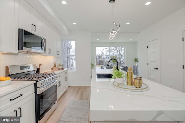 kitchen with tasteful backsplash, appliances with stainless steel finishes, white cabinets, and a sink