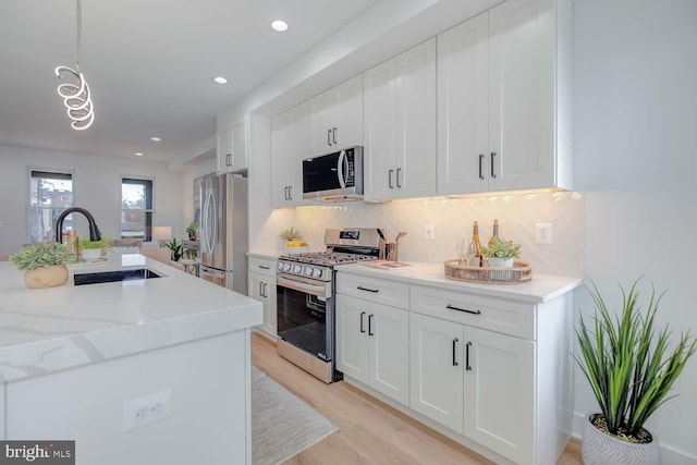 kitchen with stainless steel appliances, white cabinetry, a sink, and decorative backsplash