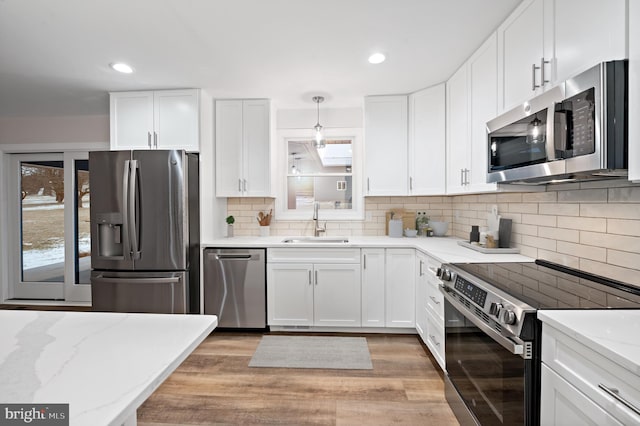 kitchen featuring appliances with stainless steel finishes, sink, hanging light fixtures, and white cabinets