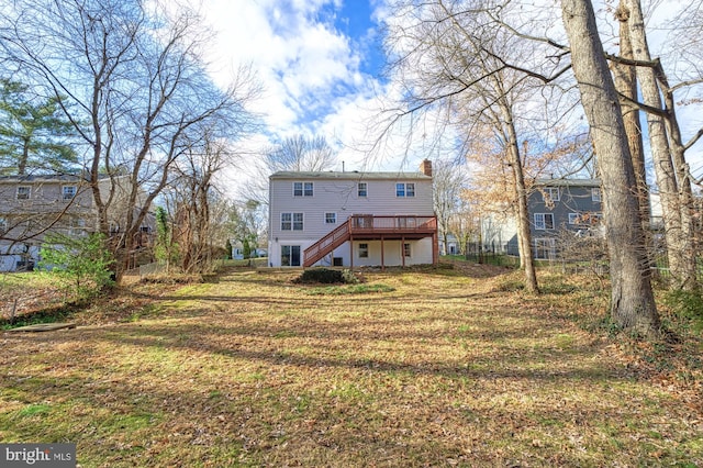 rear view of property with a deck, stairway, a chimney, and a lawn