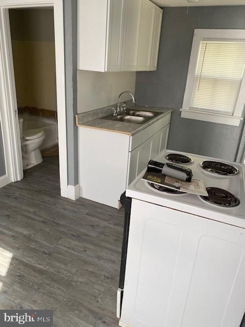 kitchen with sink, white cabinets, dark hardwood / wood-style flooring, and electric stove