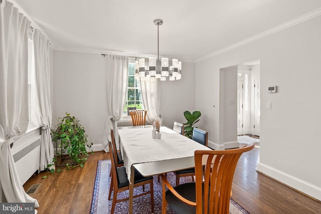 dining area featuring a chandelier, crown molding, wood finished floors, and baseboards