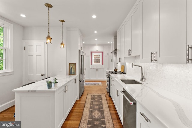 kitchen featuring stainless steel appliances, a sink, white cabinets, wood finished floors, and recessed lighting