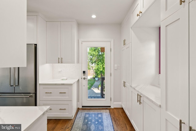kitchen with high end refrigerator, wood finished floors, white cabinets, recessed lighting, and light stone countertops