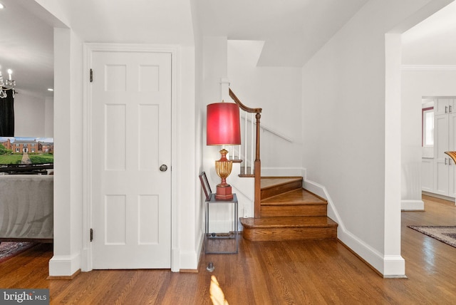 stairway with wood finished floors, a chandelier, and baseboards