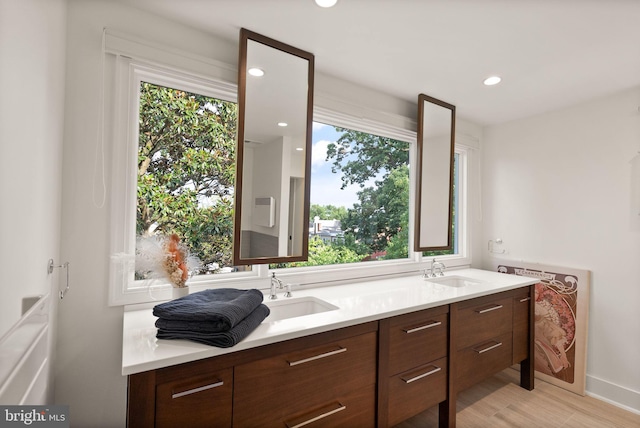 bathroom with healthy amount of natural light, wood finished floors, double vanity, and recessed lighting
