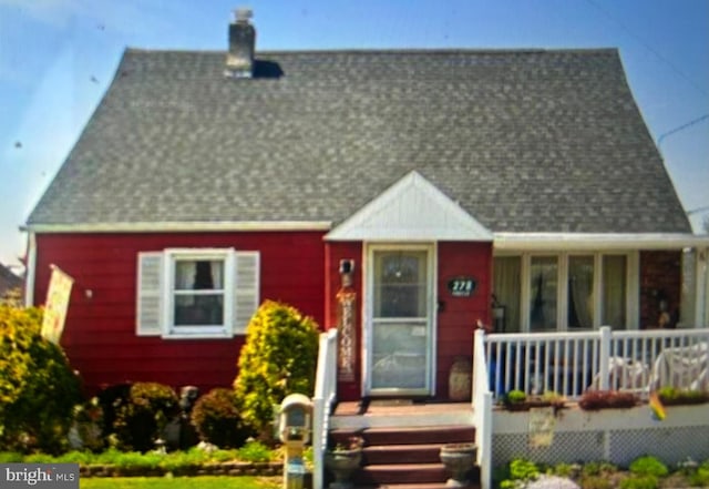 view of front of property with covered porch, roof with shingles, and a chimney