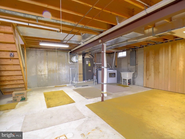 basement featuring heating unit, sink, washer / dryer, and electric panel