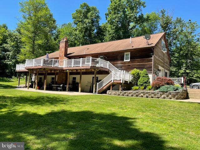 rear view of house featuring a yard, a wooden deck, and a patio