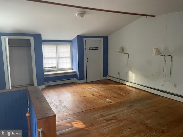 interior space featuring baseboard heating, vaulted ceiling, and hardwood / wood-style floors