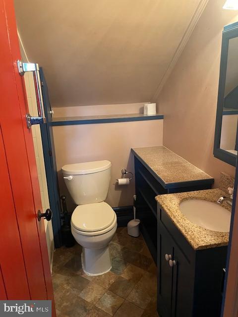 bathroom featuring toilet, vanity, crown molding, and lofted ceiling