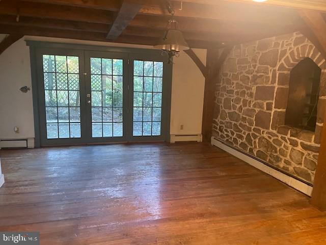 unfurnished living room featuring a baseboard heating unit, beam ceiling, a chandelier, and wood-type flooring