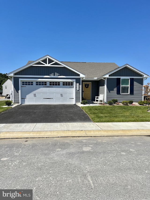 view of front of house featuring roof with shingles, a front lawn, a garage, aphalt driveway, and board and batten siding