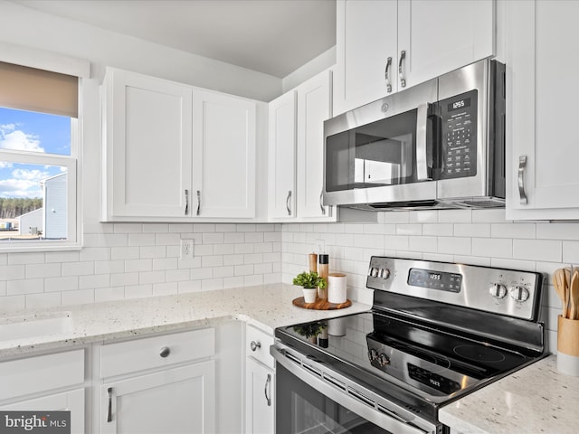 kitchen featuring backsplash, white cabinets, stainless steel appliances, and light stone counters