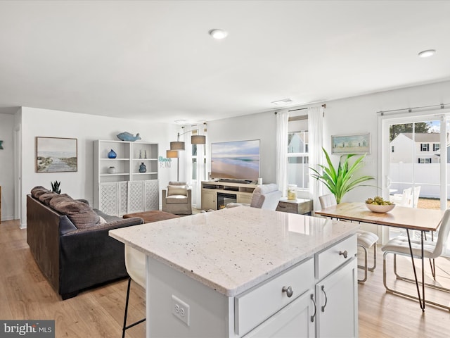 kitchen with a kitchen bar, white cabinets, a center island, and light wood finished floors