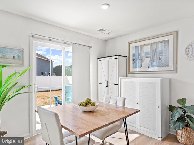 dining space featuring light wood-style flooring and visible vents