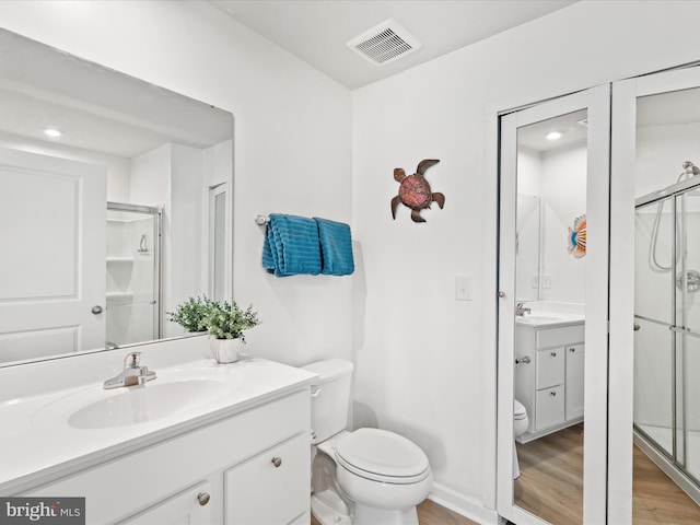 bathroom featuring a shower stall, toilet, wood finished floors, and visible vents