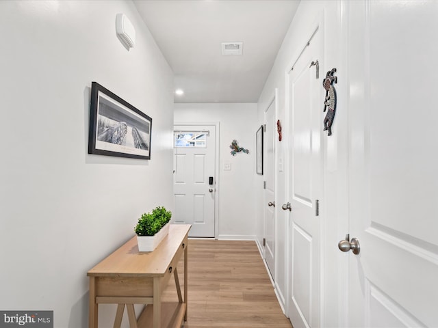 hallway with visible vents, baseboards, and light wood finished floors