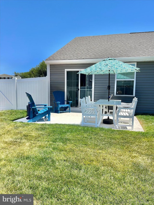 rear view of house featuring a patio, a yard, and fence