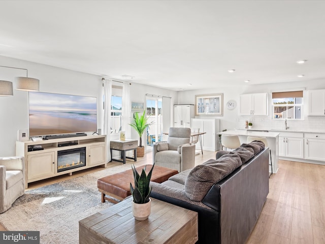 living room featuring a glass covered fireplace, recessed lighting, and light wood-type flooring