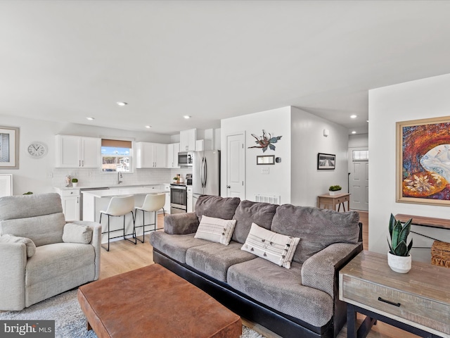 living room featuring light wood-type flooring, visible vents, and recessed lighting