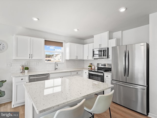 kitchen featuring a sink, light stone counters, a kitchen breakfast bar, a kitchen island, and stainless steel appliances