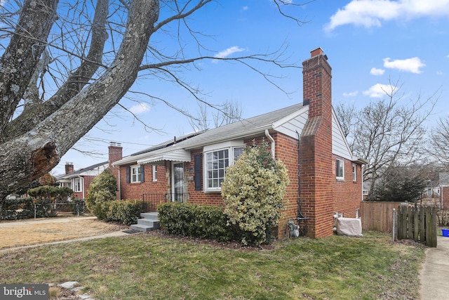 view of front facade with a chimney, fence, a front lawn, and brick siding