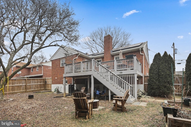 back of house featuring a deck, brick siding, fence, stairway, and a chimney