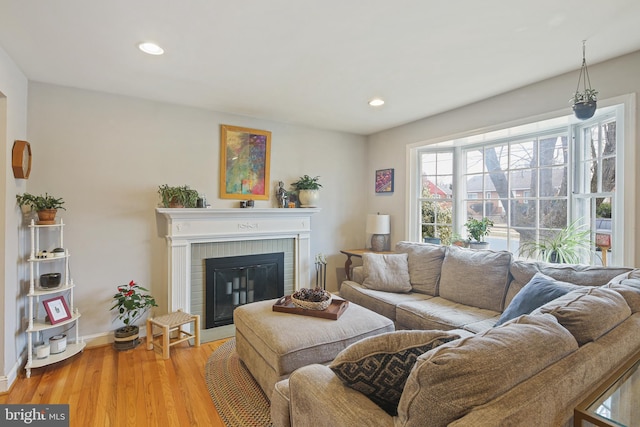 living area featuring recessed lighting, a brick fireplace, wood finished floors, and baseboards