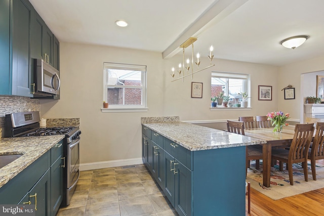 kitchen featuring a peninsula, a kitchen breakfast bar, appliances with stainless steel finishes, light stone countertops, and decorative light fixtures