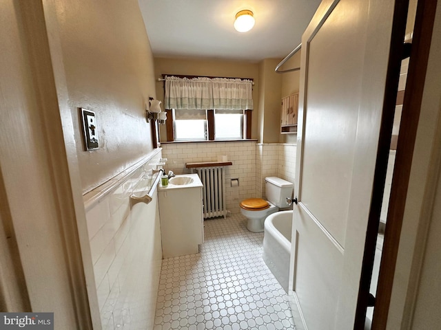 full bathroom with a tub to relax in, radiator, toilet, wainscoting, and vanity