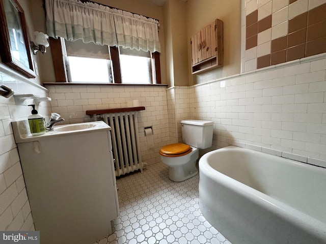 full bath with a washtub, toilet, vanity, tile walls, and radiator heating unit