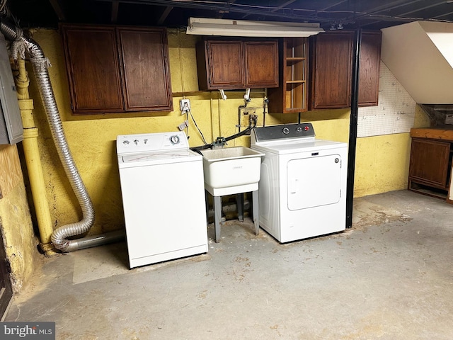 clothes washing area with cabinet space, washer and dryer, and a sink