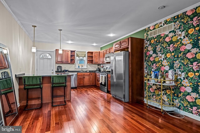 kitchen featuring ornamental molding, stainless steel appliances, a breakfast bar, and sink