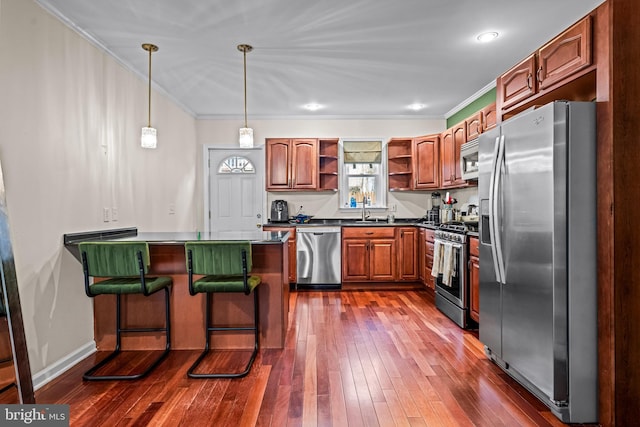 kitchen featuring pendant lighting, a breakfast bar area, appliances with stainless steel finishes, ornamental molding, and kitchen peninsula