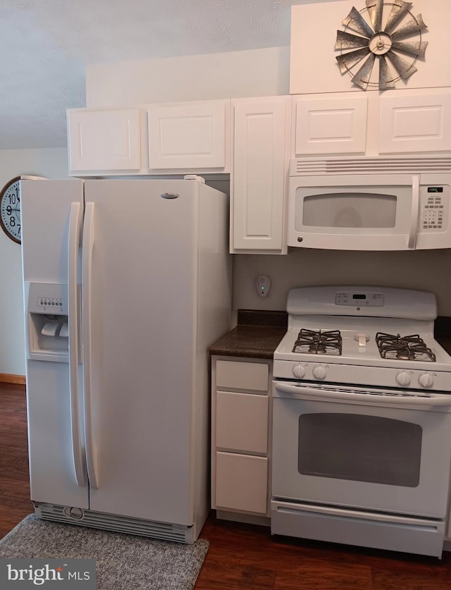 kitchen featuring dark countertops, white appliances, white cabinets, and dark wood-style flooring