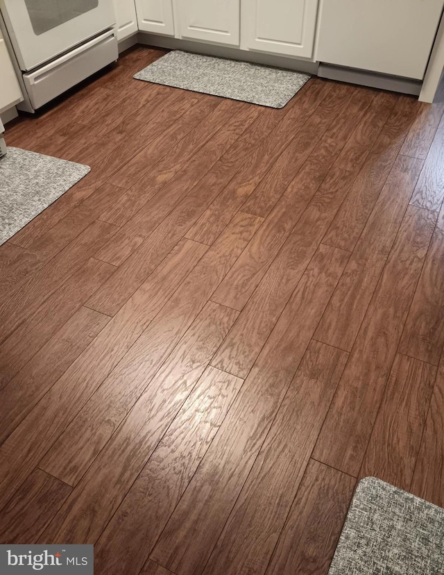 details with dark wood-type flooring, white cabinetry, and range