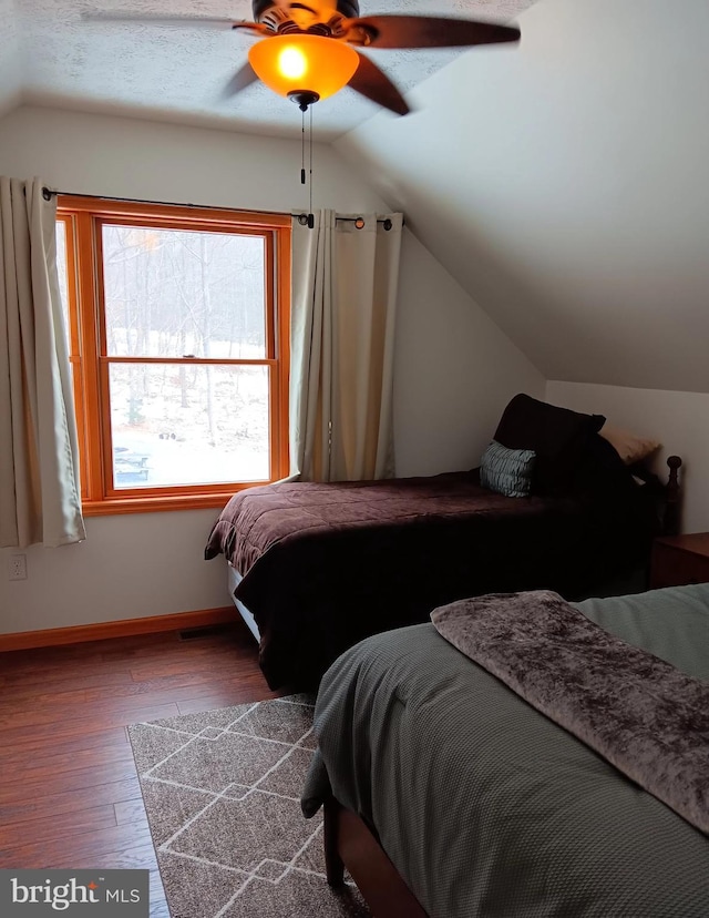 bedroom with a ceiling fan, vaulted ceiling, baseboards, and wood finished floors