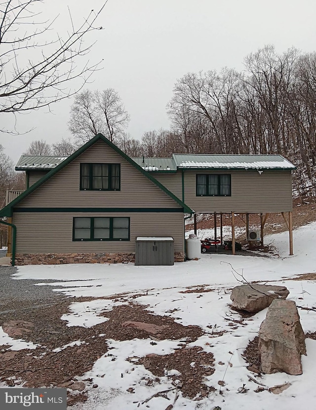 snow covered back of property featuring a garage