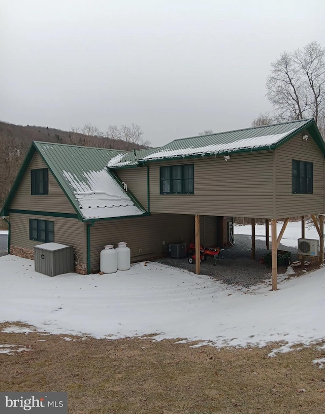 snow covered property featuring metal roof, ac unit, and central air condition unit