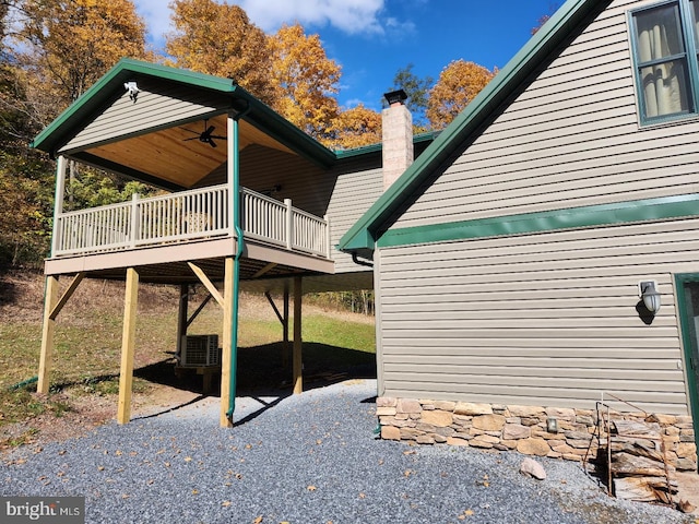 view of home's exterior featuring ceiling fan, central AC, a chimney, and a wooden deck