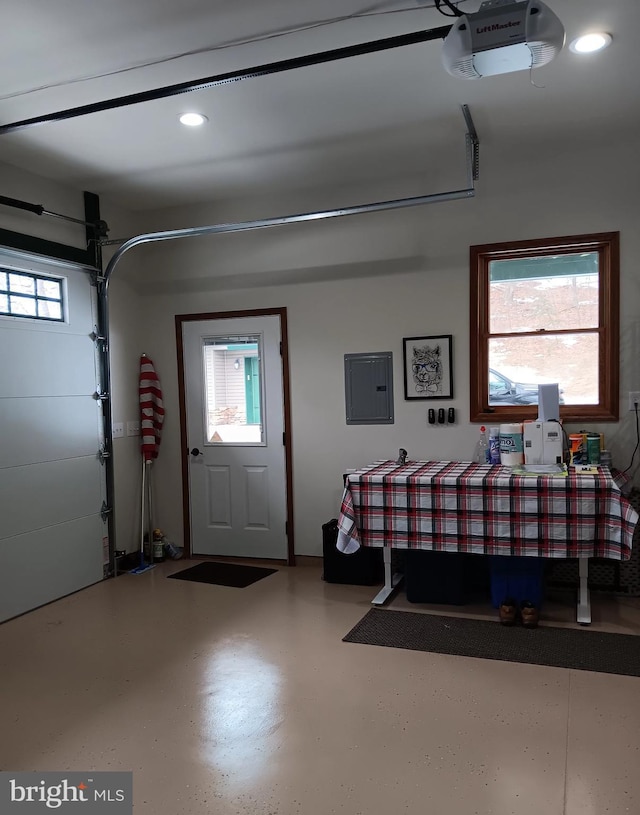 garage with a garage door opener, recessed lighting, and electric panel