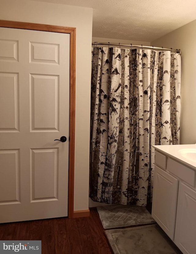 bathroom with a textured ceiling, wood finished floors, and vanity