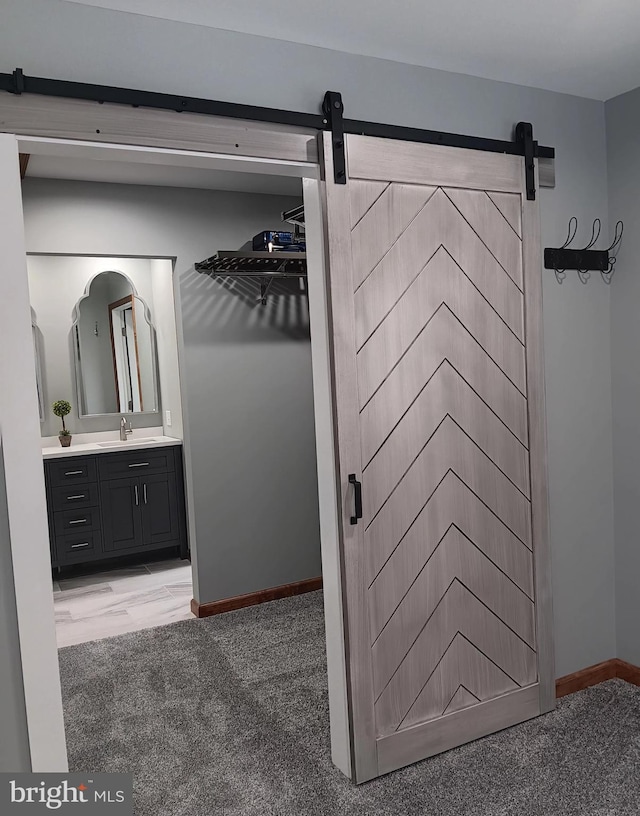 interior space with light carpet, a sink, and a barn door