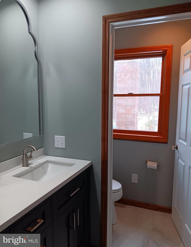 bathroom with toilet, baseboards, and vanity