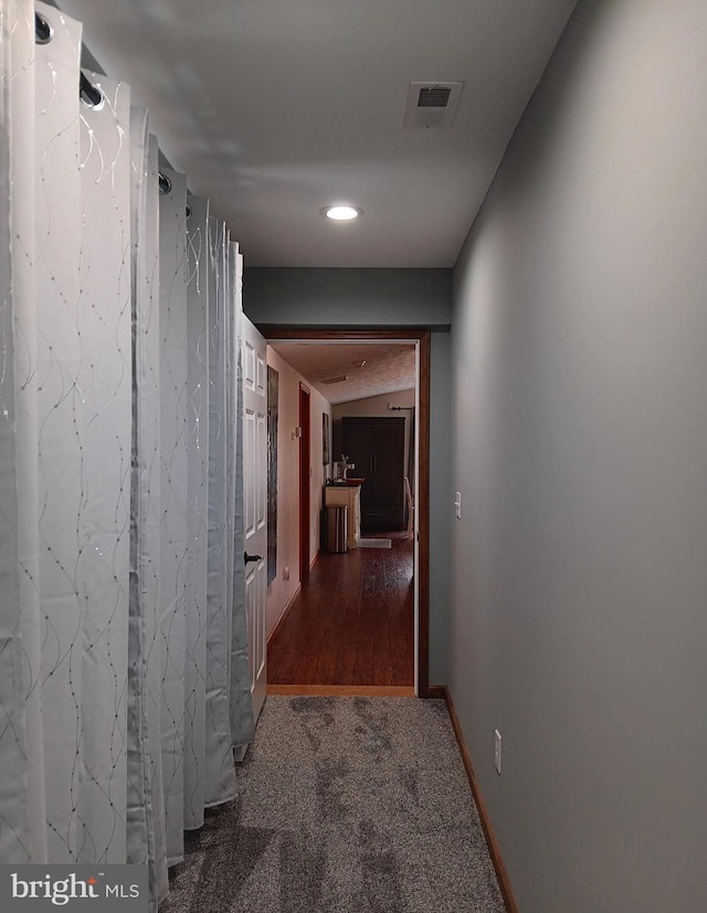 hall featuring carpet, visible vents, and baseboards