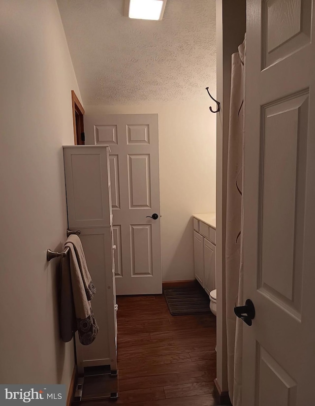 hallway featuring baseboards and dark wood-style flooring