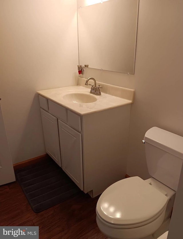 bathroom featuring toilet, baseboards, wood finished floors, and vanity